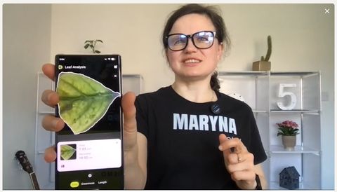 Dr Maryna Kuzmenko holding a phone showing the Petiole Pro Leaf Analysis result screen.