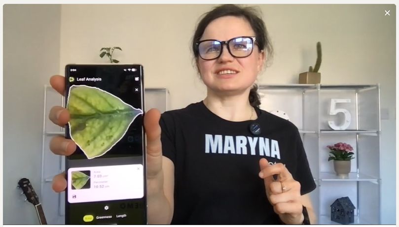 Dr Maryna Kuzmenko holding a phone showing the Petiole Pro Leaf Analysis result screen.