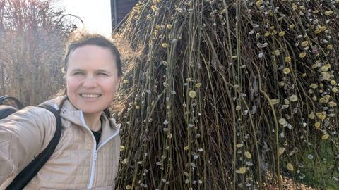 Dr Maryna Kuzmenko, founder of Petiole, smiling outdoors in front of a willow covered in catkins.