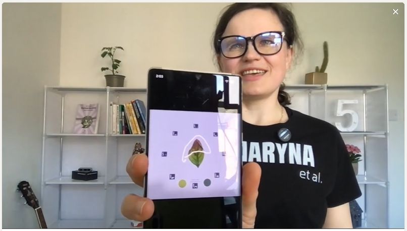 Dr Maryna Kuzmenko holding a phone that shows the Petiole Pro capture screen with a leaf inside a ring of ArUco calibration markers.